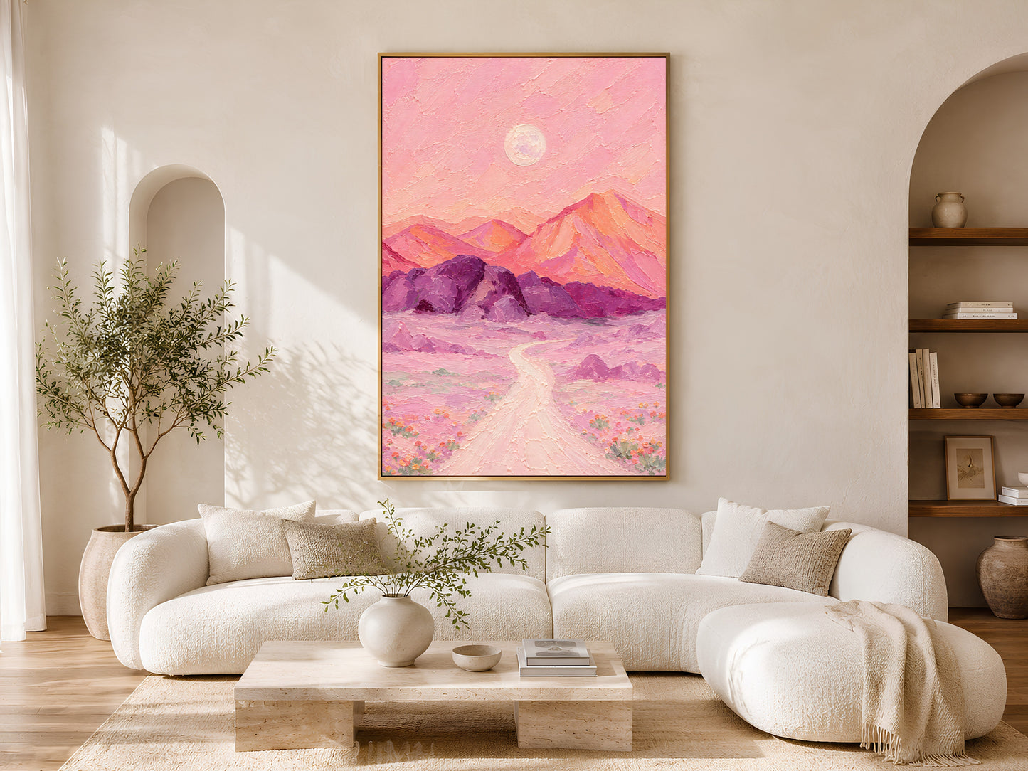 Pink desert moon wall art print framed above a cream sofa in a sunlit living room.
