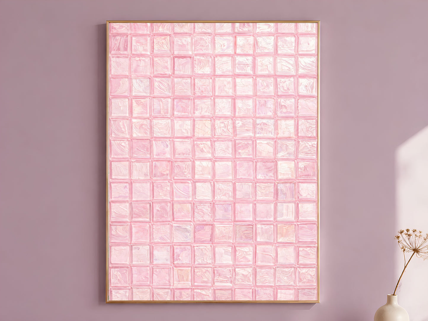 Blush pink impasto mosaic tile wall art in a thin gold frame leaning against a dusty mauve wall with a dried allium stem in a cream vase beside it
