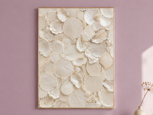 Shell collector wall art in a thin gold frame hanging on a dusty mauve wall, styled with a small dried flower vase.
