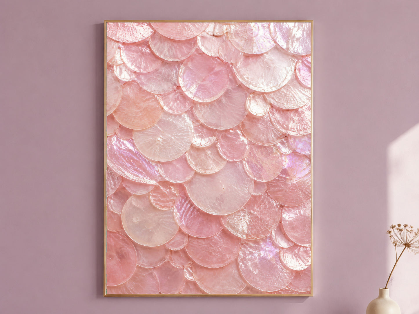 Pink capiz shell wall art in a thin gold frame hanging on a dusty mauve wall, styled with a small dried flower vase.