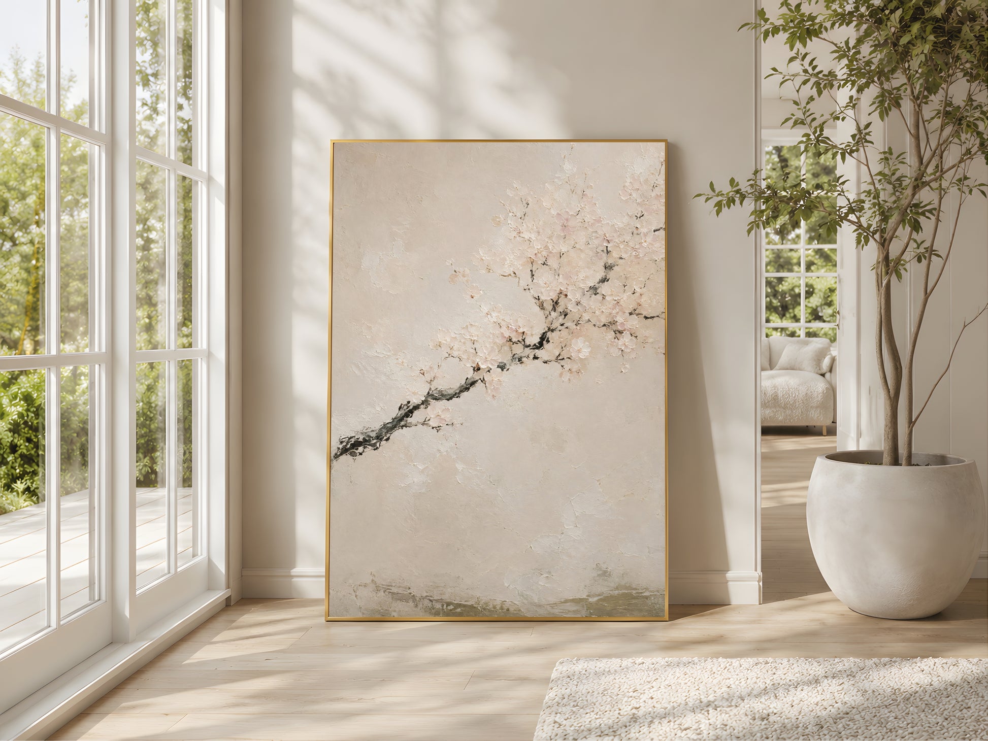 Japandi cherry blossom impasto print in a gold frame beside large windows in a bright minimal living room with olive tree and warm natural light
