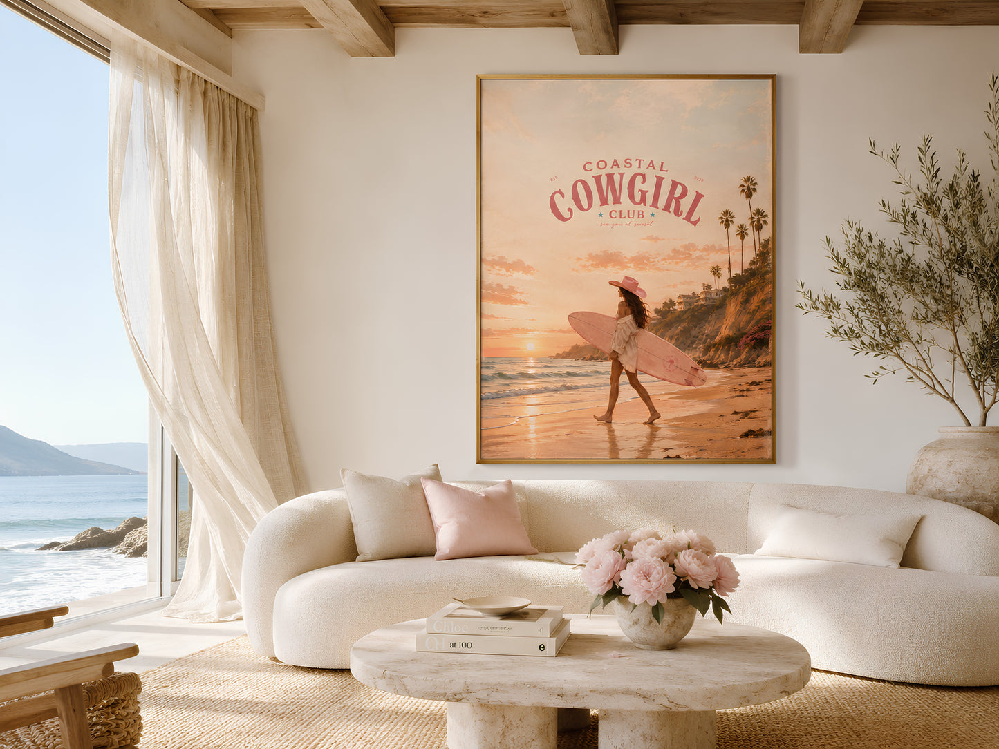 Coastal Cowgirl print in a bright coastal living room with white arched walls, linen sofa, pink flowers, and ocean view window
