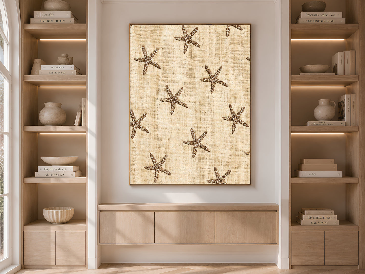 Embroidered starfish wall art framed above a console table between built-in bookshelves