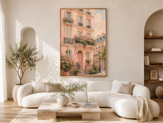 Framed pink Paris building impasto painting print in a warm neutral living room with white curved sofa, round coffee table and soft natural light
