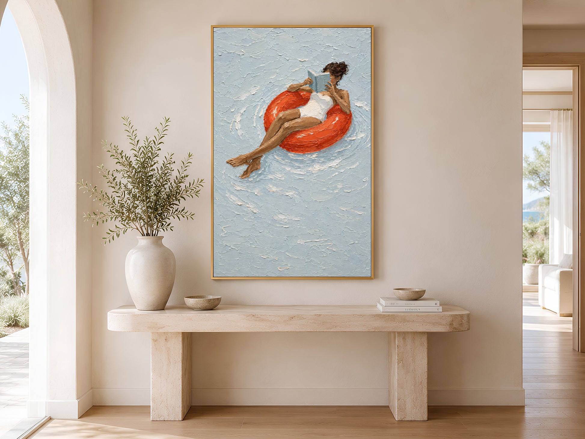 Gold-framed woman on red pool float print above a minimalist console table with a tall round white vase in a neutral entryway with warm natural light
