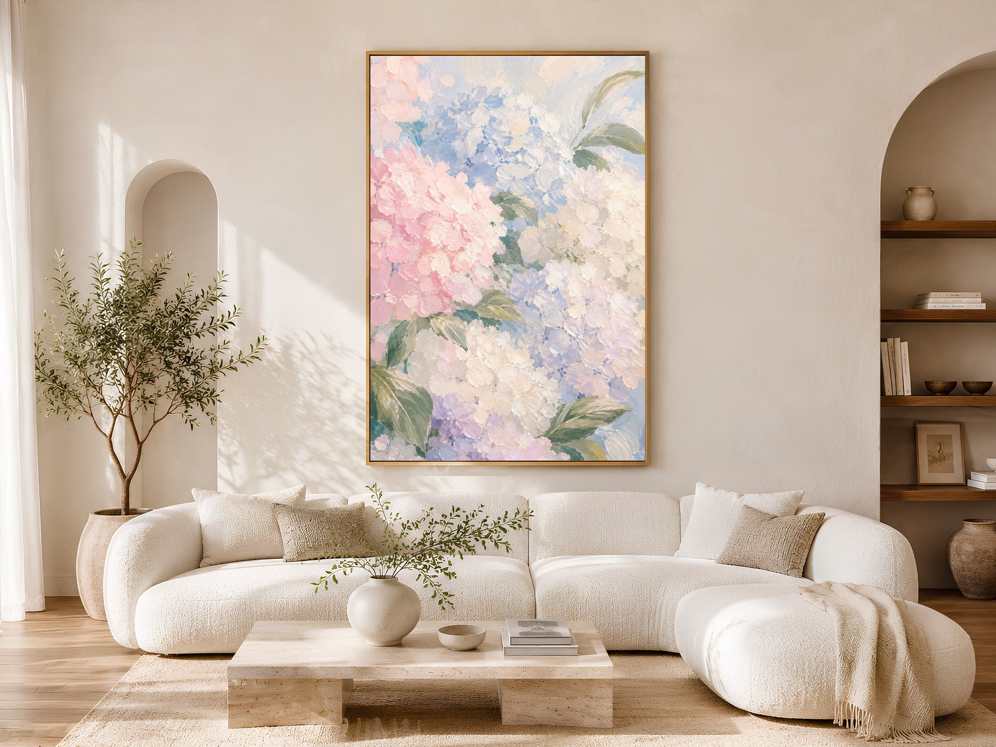 Pink and blue hydrangea wall art in gold frame above a cream sofa in a bright neutral living room with arched shelving