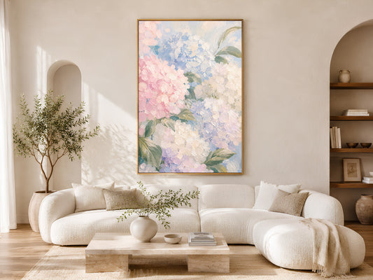 Pink and blue hydrangea wall art in gold frame above a cream sofa in a bright neutral living room with arched shelving