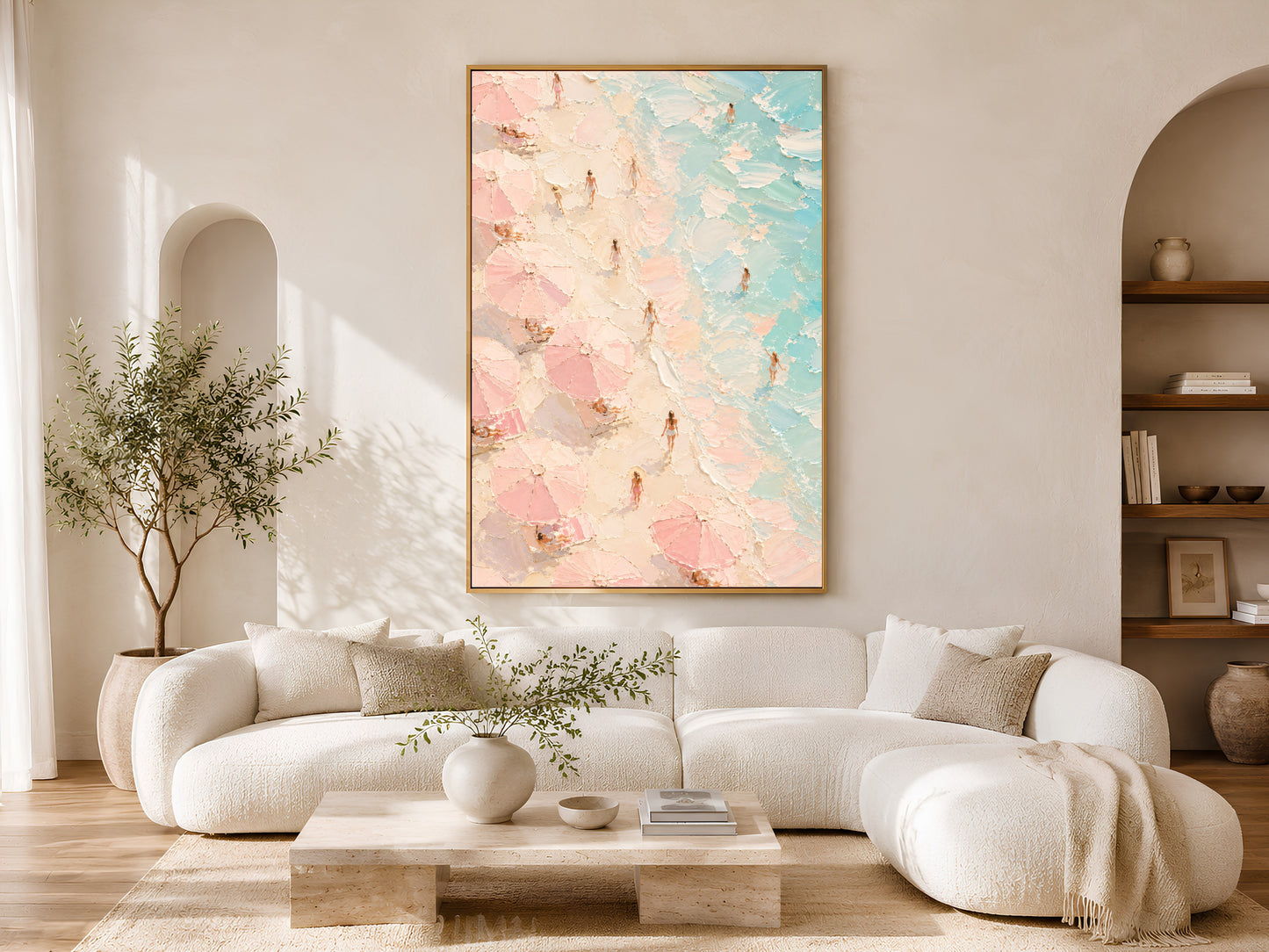 Aerial beach impasto art print in a gold frame above a white curved sofa in a warm neutral living room with olive tree and arch detail
