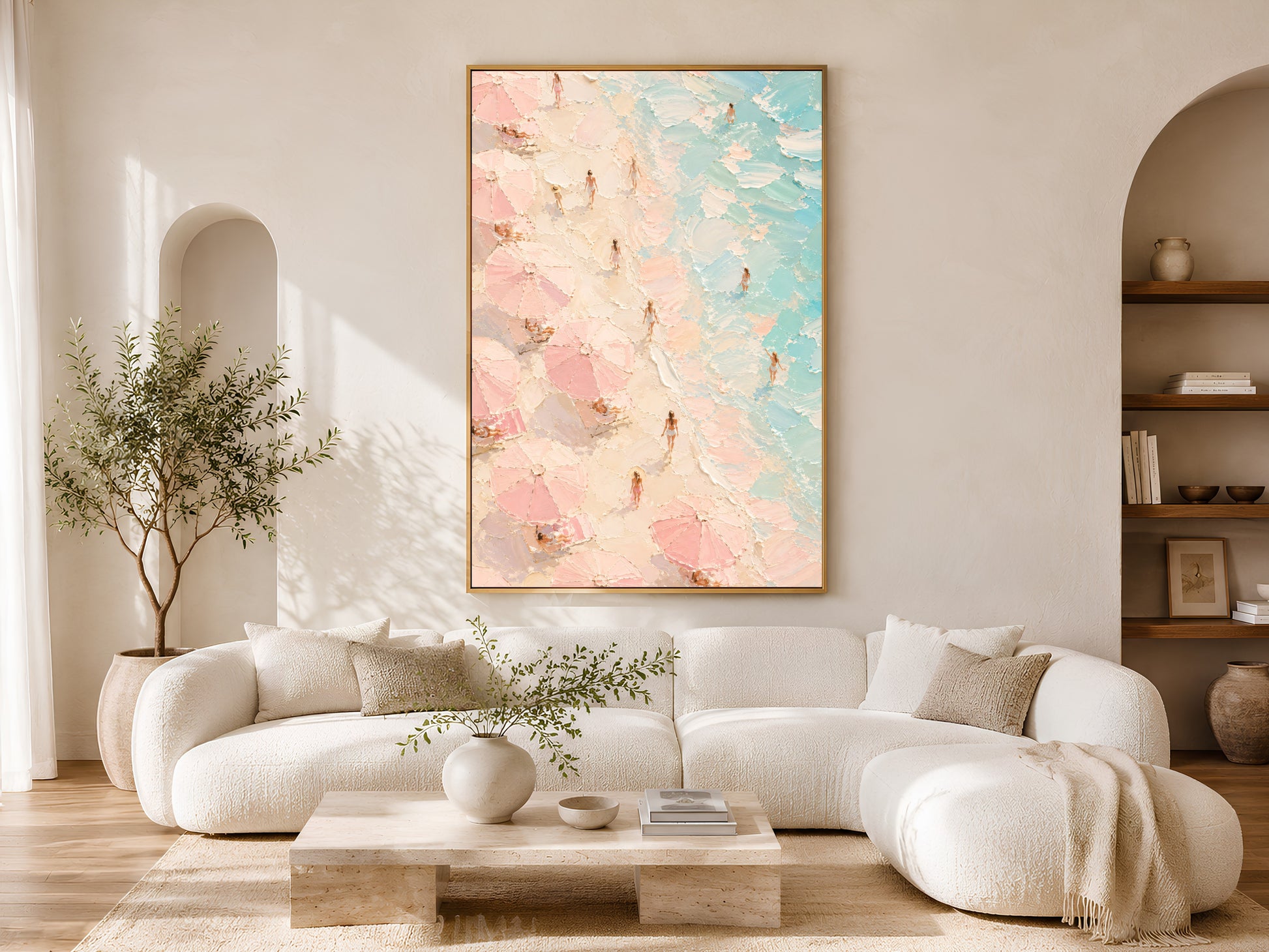 Aerial beach impasto art print in a gold frame above a white curved sofa in a warm neutral living room with olive tree and arch detail
