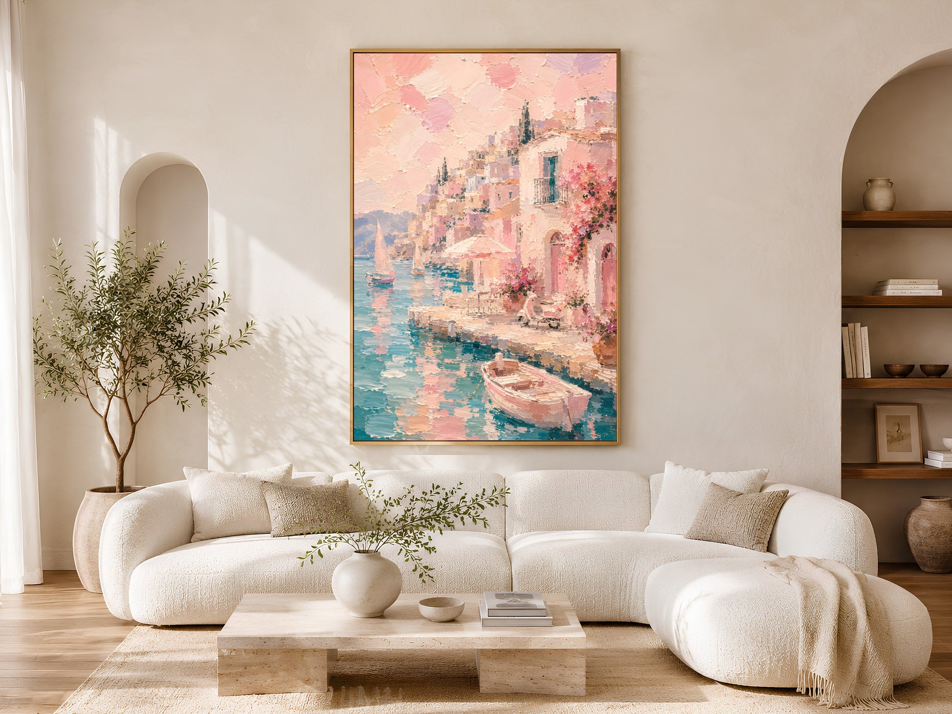 Italian coastal village print in gold frame above a cream sofa in a bright neutral living room with arched shelving and olive tree