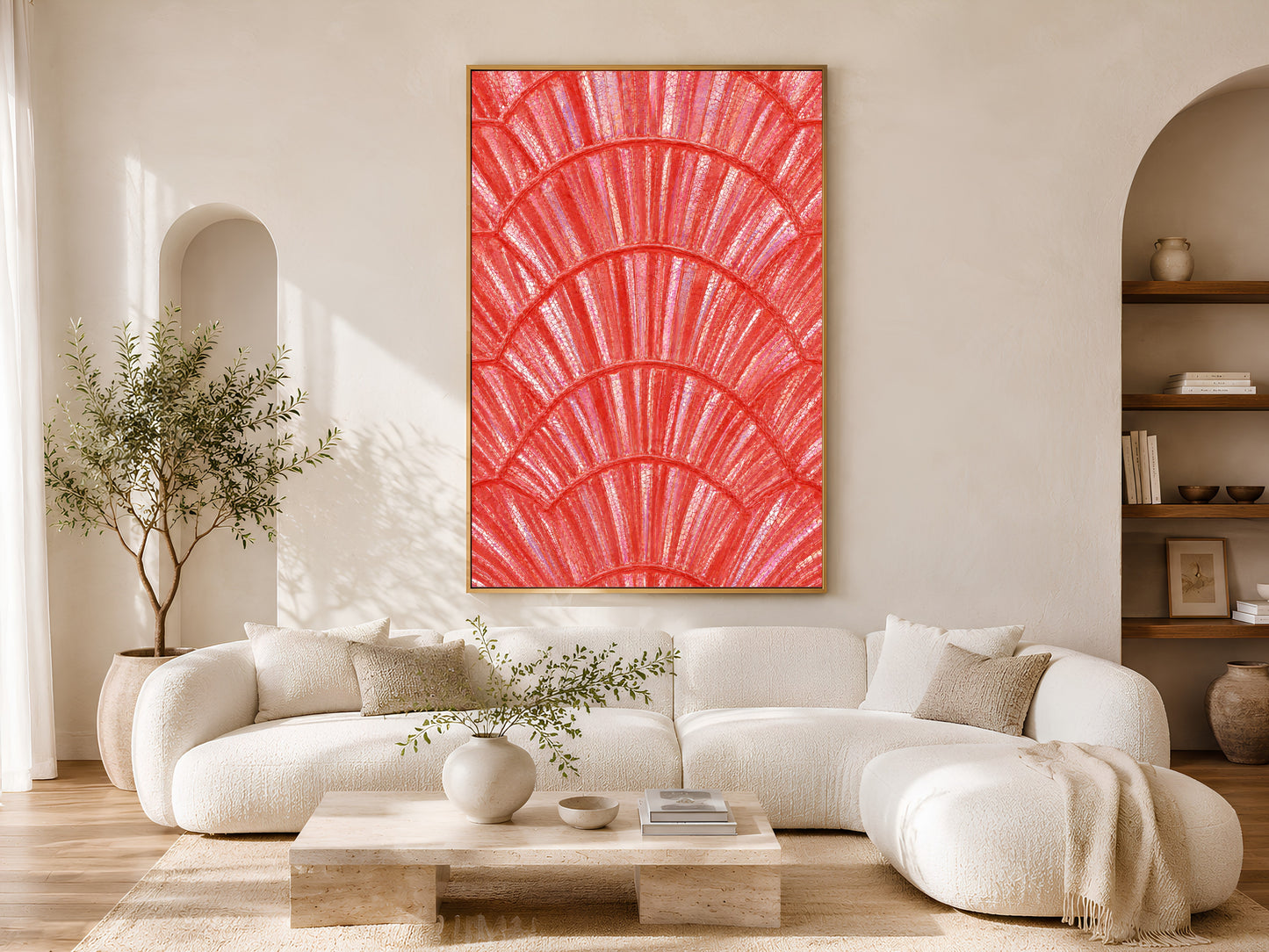 Bold coral shell wall art in gold frame above a cream sofa in a bright neutral living room with arched shelving and olive tree
