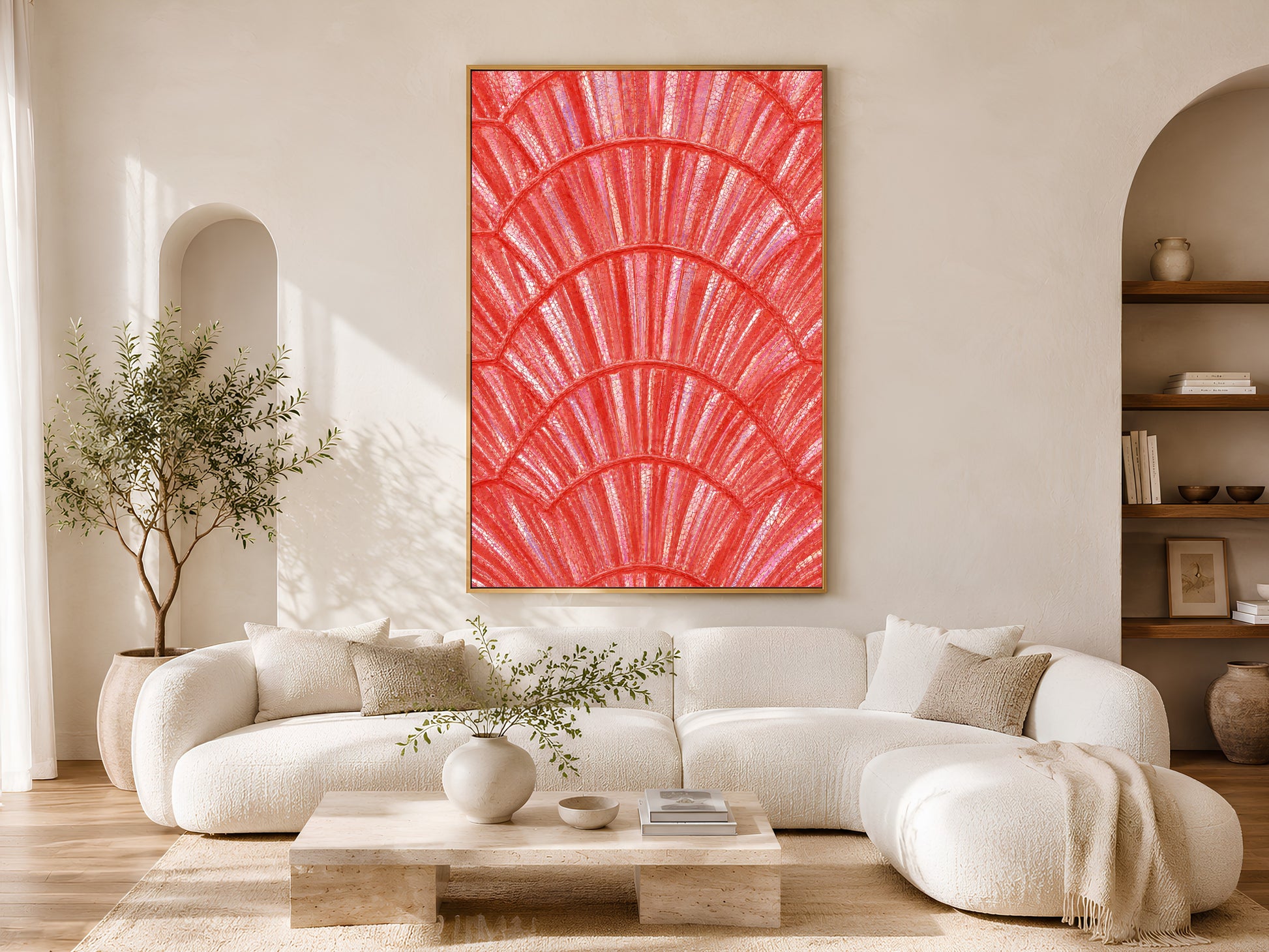 Bold coral shell wall art in gold frame above a cream sofa in a bright neutral living room with arched shelving and olive tree