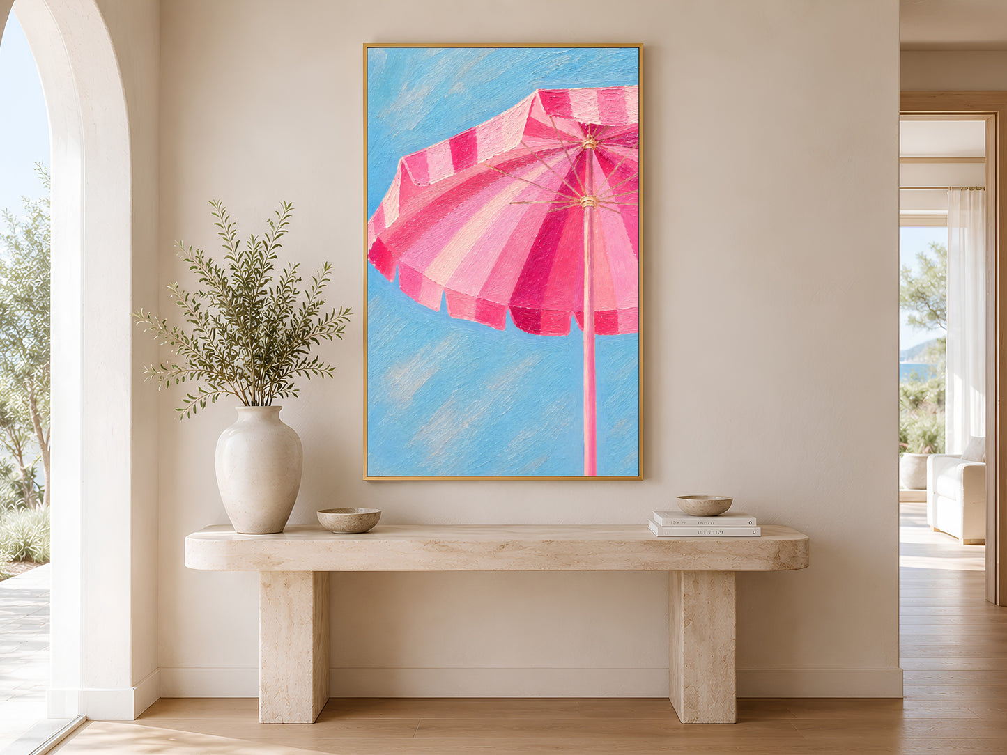 Pink cabana umbrella wall art printable hanging above a beige console table in a bright Mediterranean-inspired hallway with coastal decor.