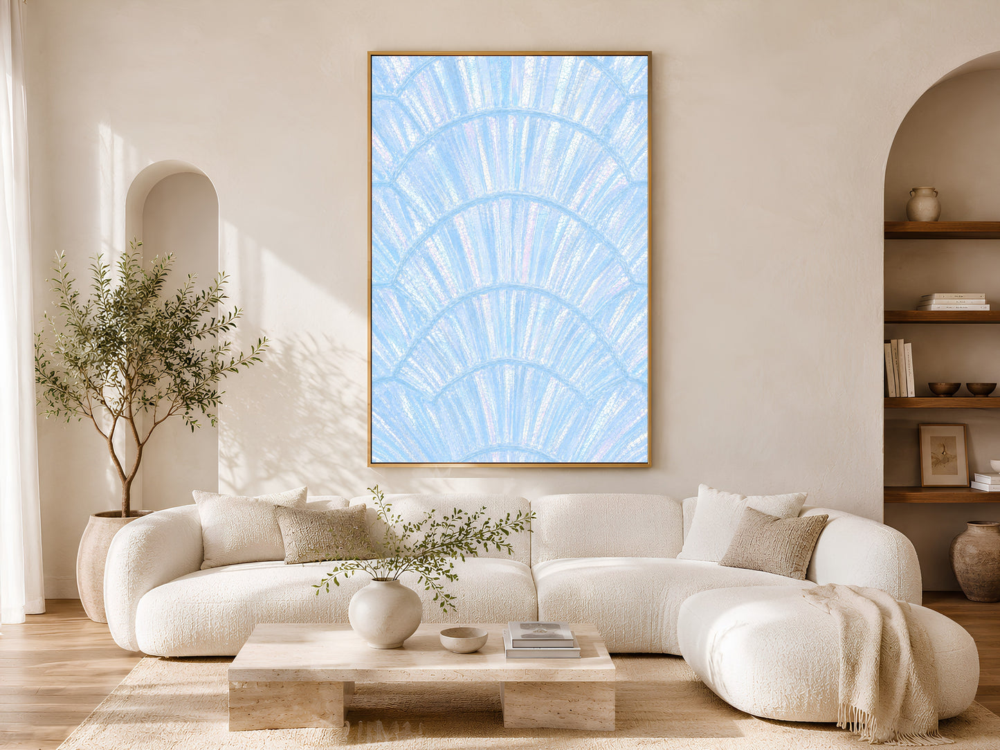 Blue capiz shell print in gold frame above a cream sofa in a bright neutral living room with arched shelving and olive tree