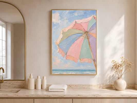 Pastel beach umbrella print framed in gold above console table in neutral hallway
