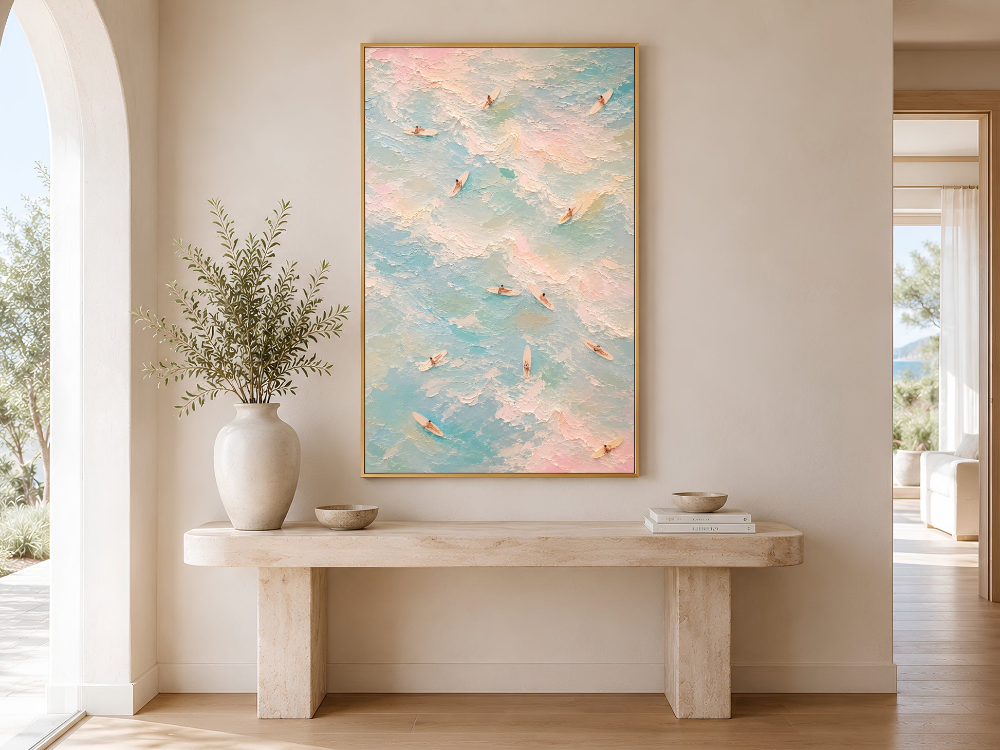 Coastal aerial surfer print in gold frame in a bright neutral living room with tall window and ceramic vase
