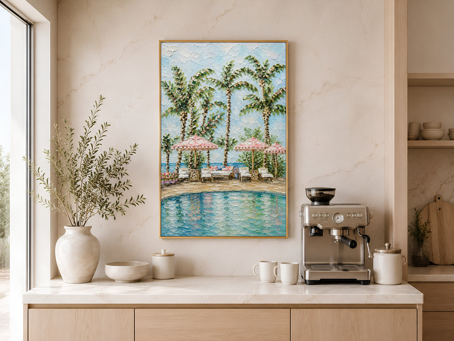 Gold-framed tropical palm tree cabana pool print above a light wood kitchen counter with a coffee station, neutral cabinetry, and a large round ceramic vase with greenery
