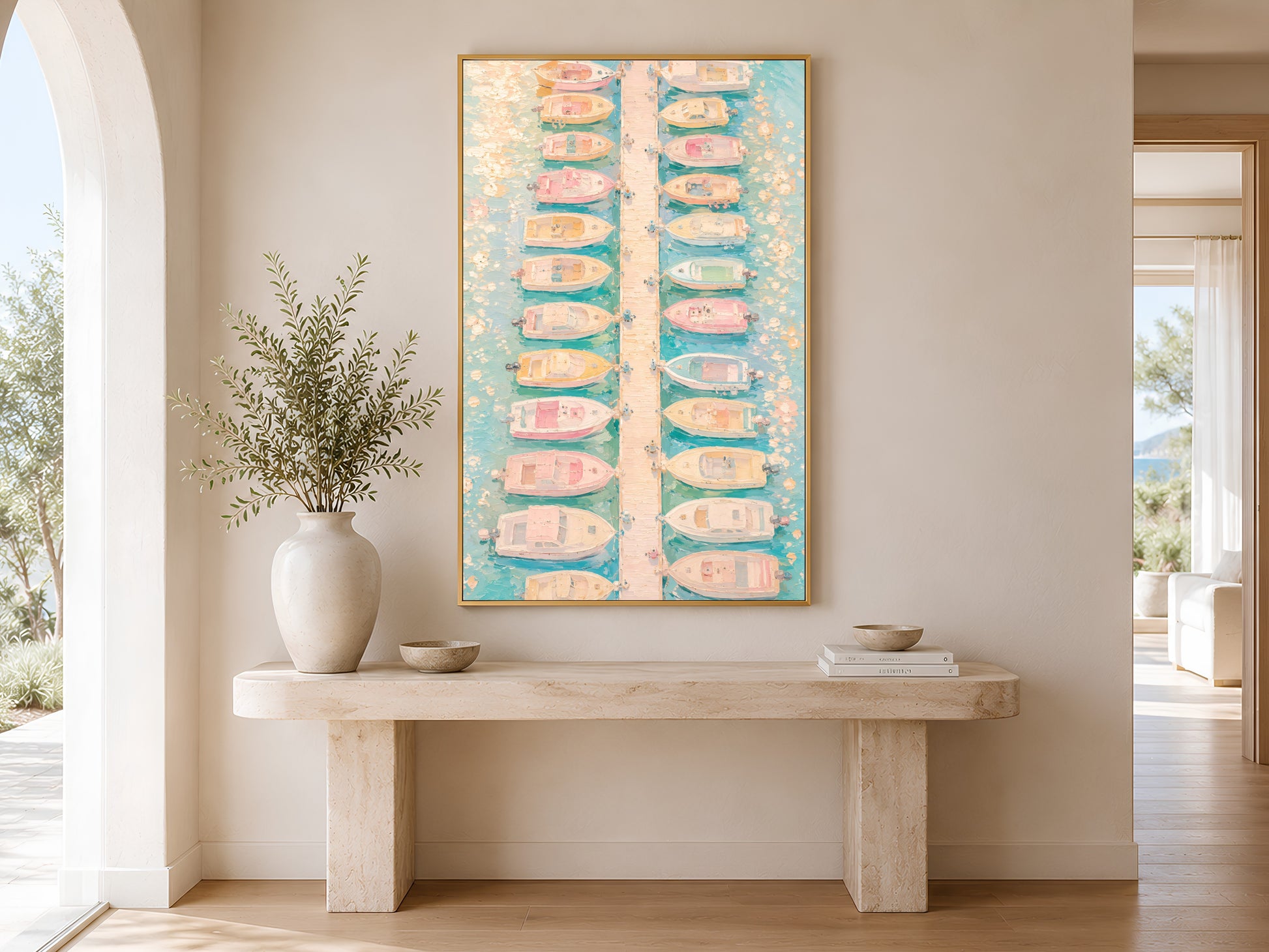 Aerial marina pastel print in gold frame above a marble console table in a minimal bright neutral hallway