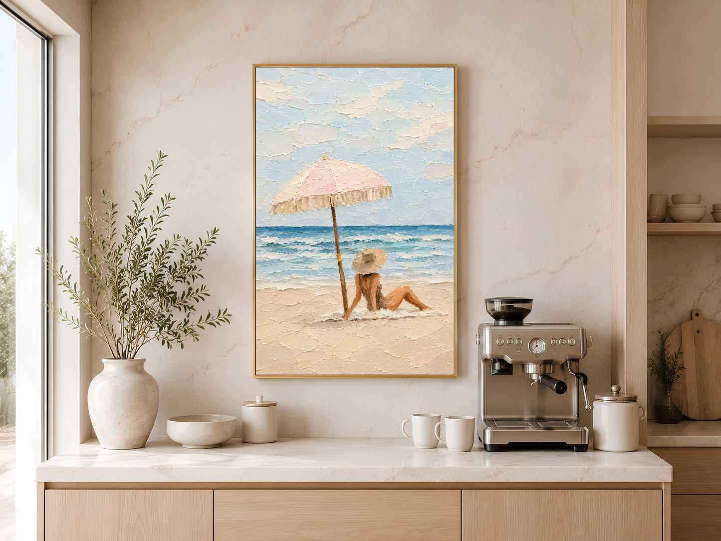 Framed beach scene wall art leaning beside a coffee machine on a cream sideboard with white ceramic vases and warm neutral kitchen tones
