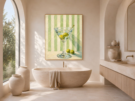Martini glass print in gold frame above a freestanding bathtub with arched window
