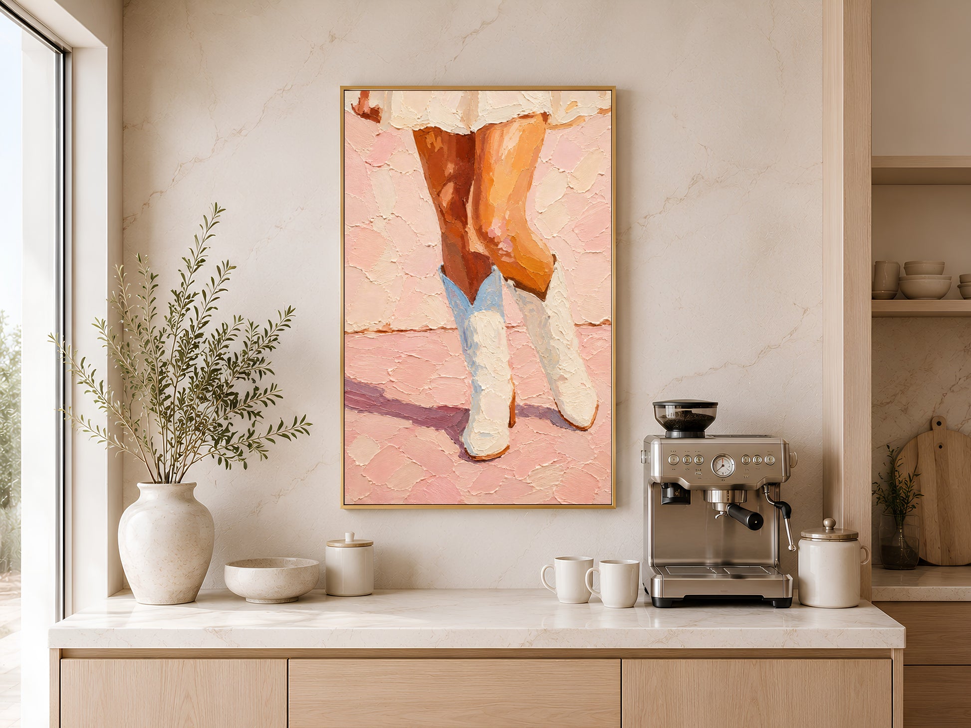 Framed pink cowgirl boots impasto print displayed above a wooden sideboard with ceramic vases and coffee machine in a warm neutral kitchen space
