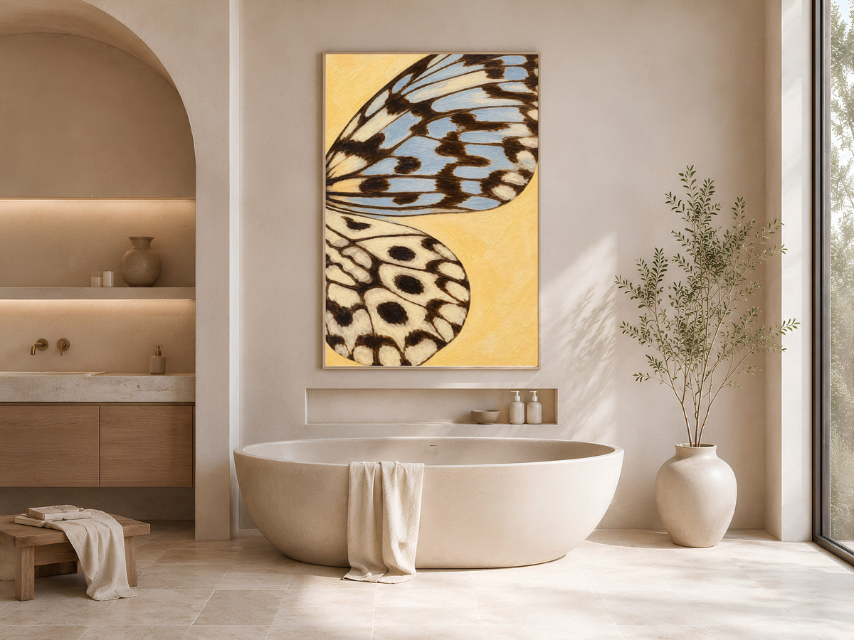 Butter yellow butterfly wing art print framed above a freestanding tub in a warm neutral bathroom
