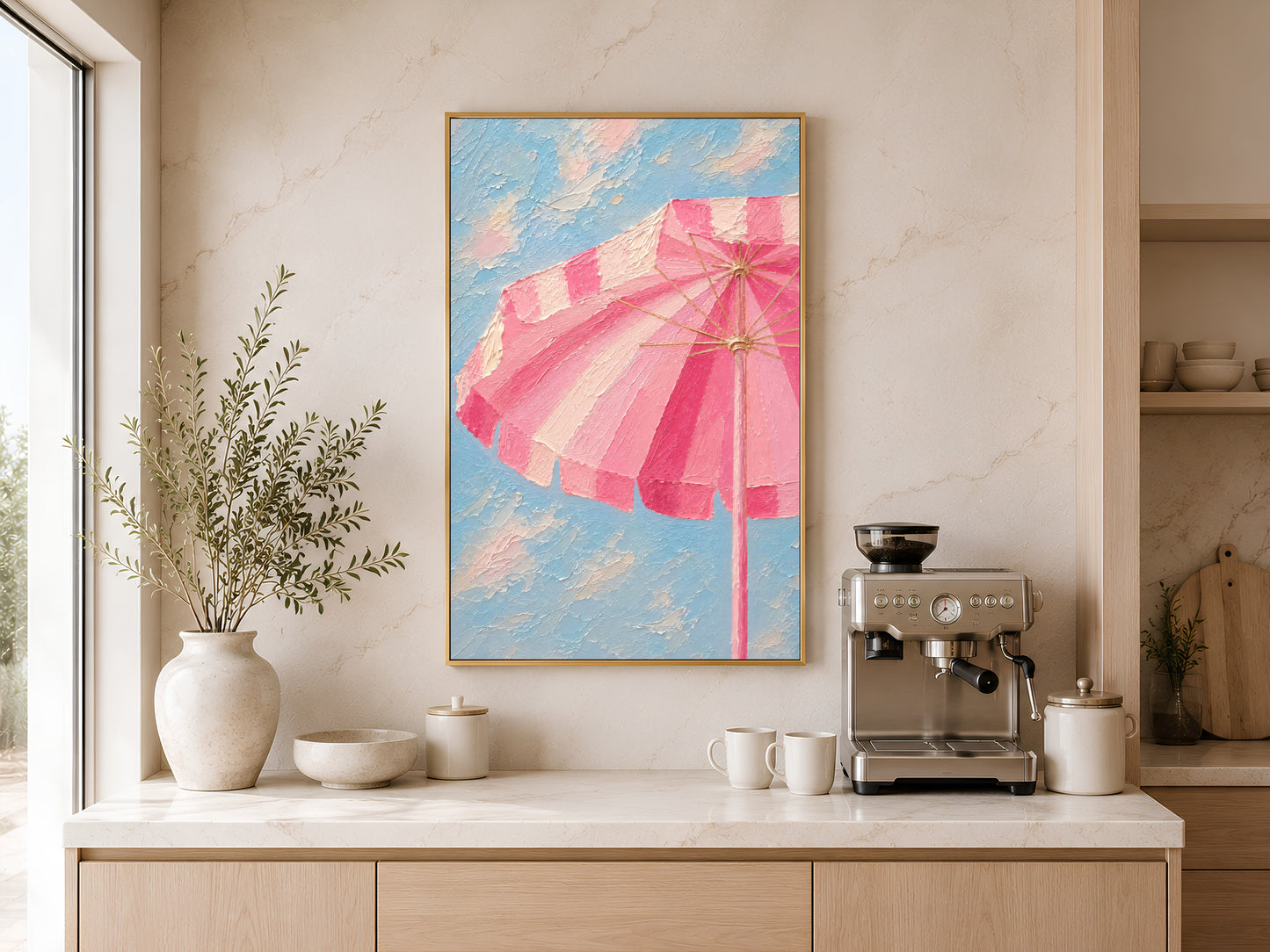 Framed pink beach umbrella wall art on a warm white wall above a kitchen sideboard with ceramic vases and coffee machine
