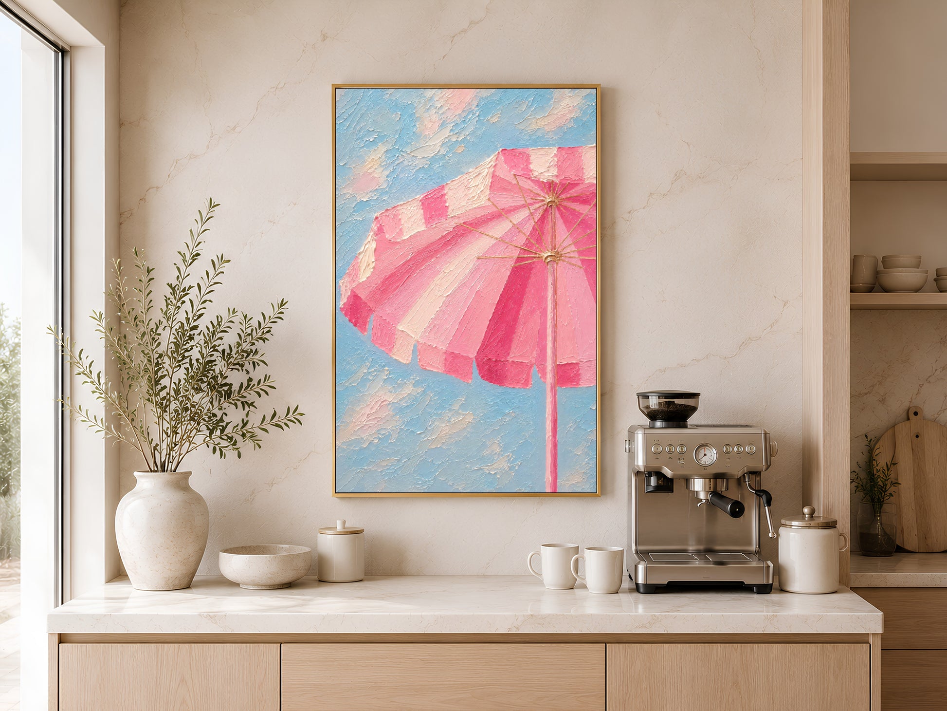 Framed pink beach umbrella wall art on a warm white wall above a kitchen sideboard with ceramic vases and coffee machine
