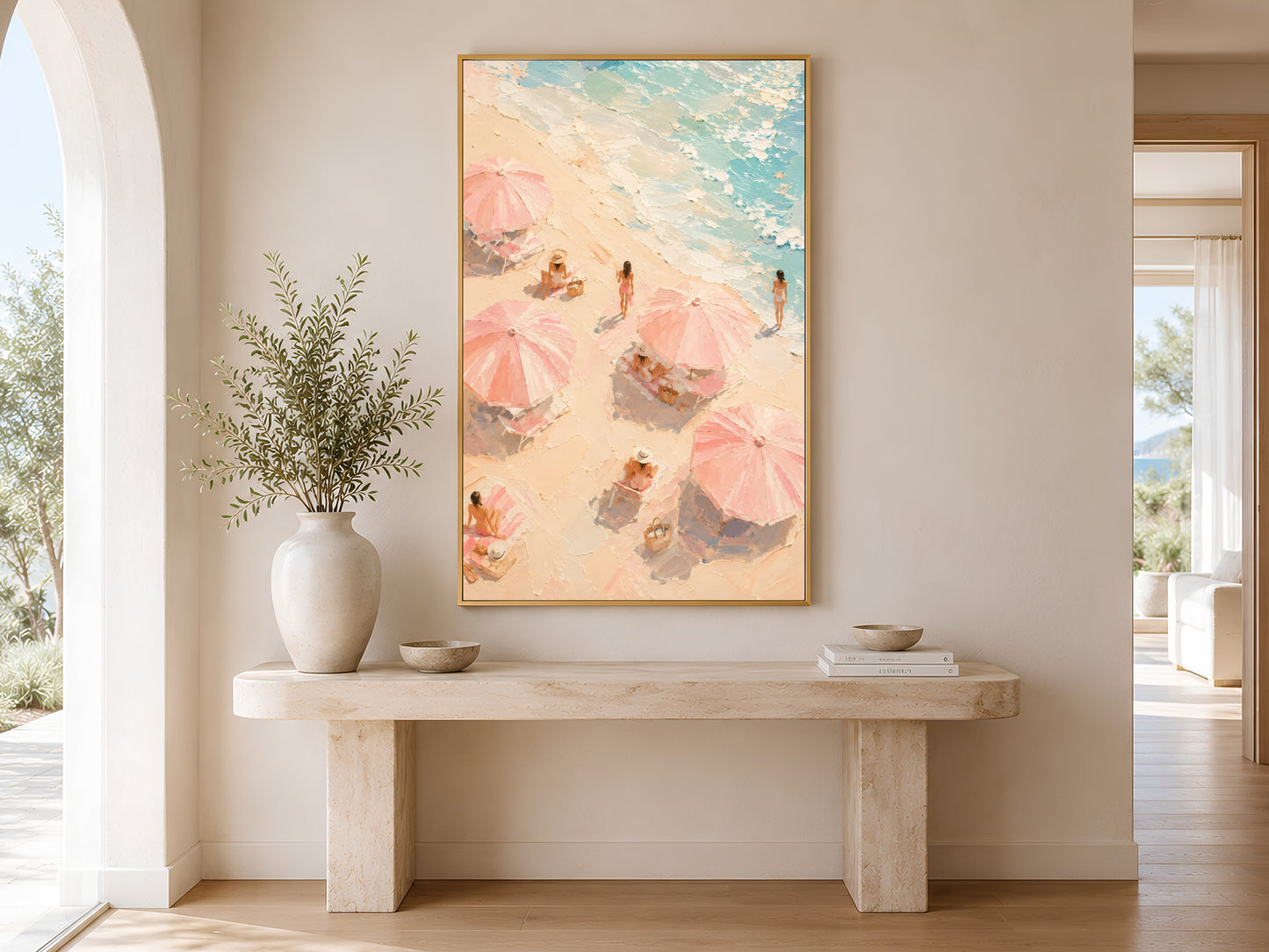 Aerial beach scene print in gold frame above a marble console table in a minimal warm neutral hallway