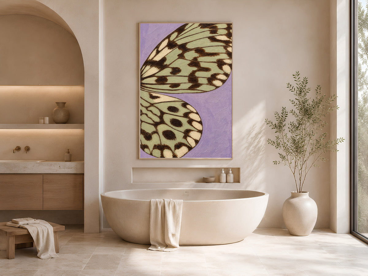 Lavender sage green butterfly wing art print framed above a freestanding tub in a warm neutral bathroom