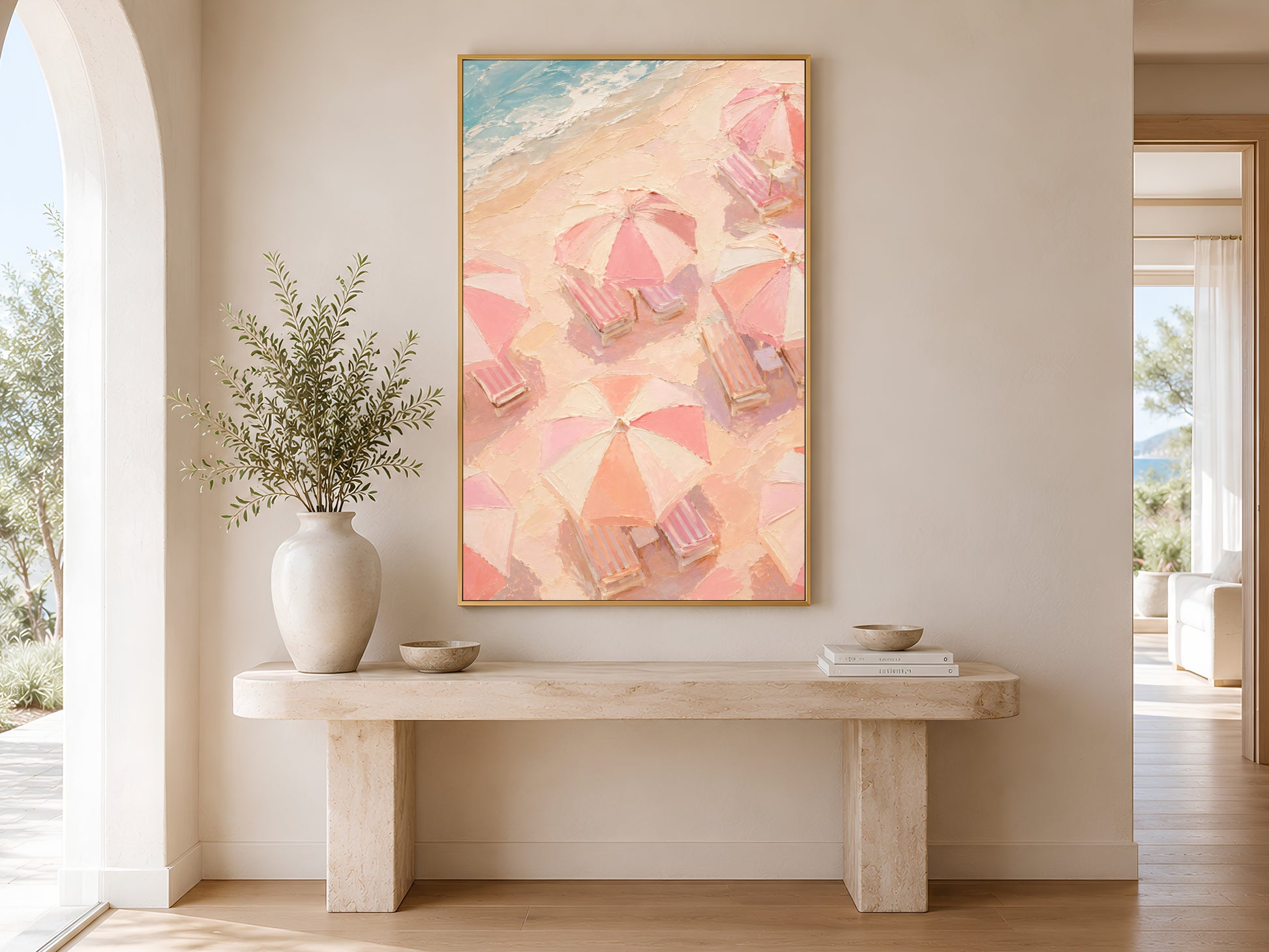 
Pink aerial beach umbrella print in gold frame above a marble console table in a minimal bright neutral hallway