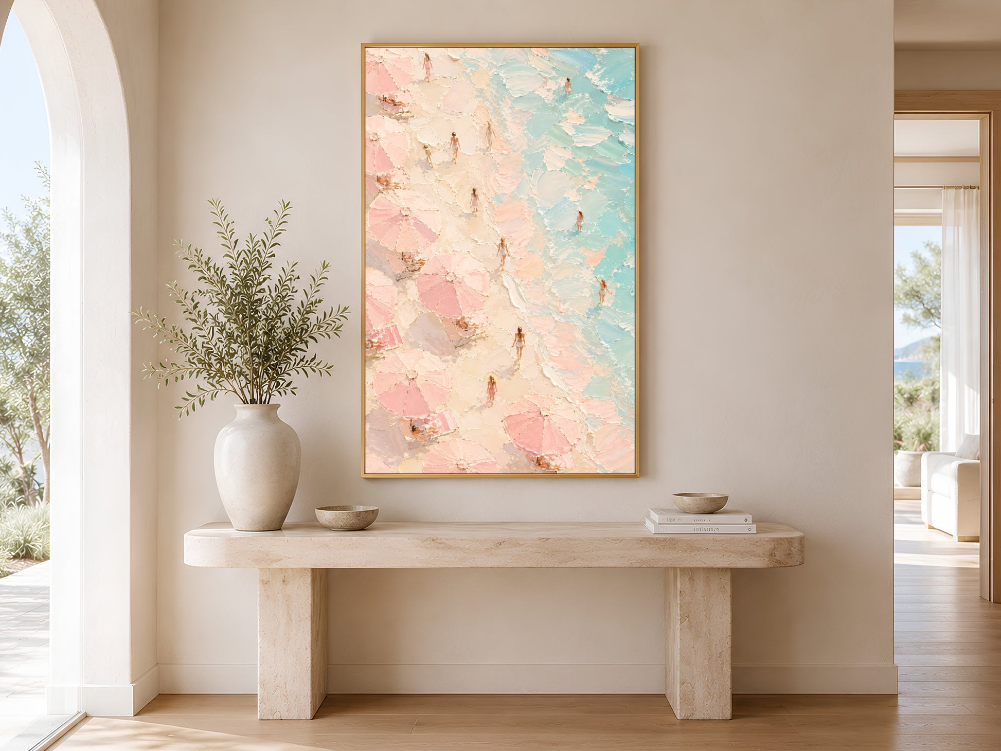 Framed aerial beach painting print in pink and teal hanging in a bright Scandinavian entryway with arched doorway and cream console table
