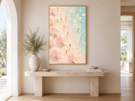 Framed aerial beach painting print in pink and teal hanging in a bright Scandinavian entryway with arched doorway and cream console table
