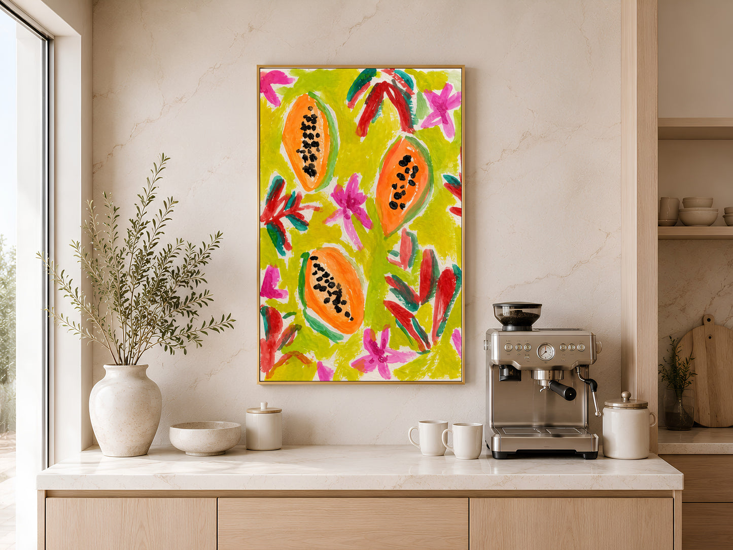 Colorful papaya print in a gold frame displayed above a light wood sideboard in a modern kitchen with neutral tones, pendant lights, and warm natural light
