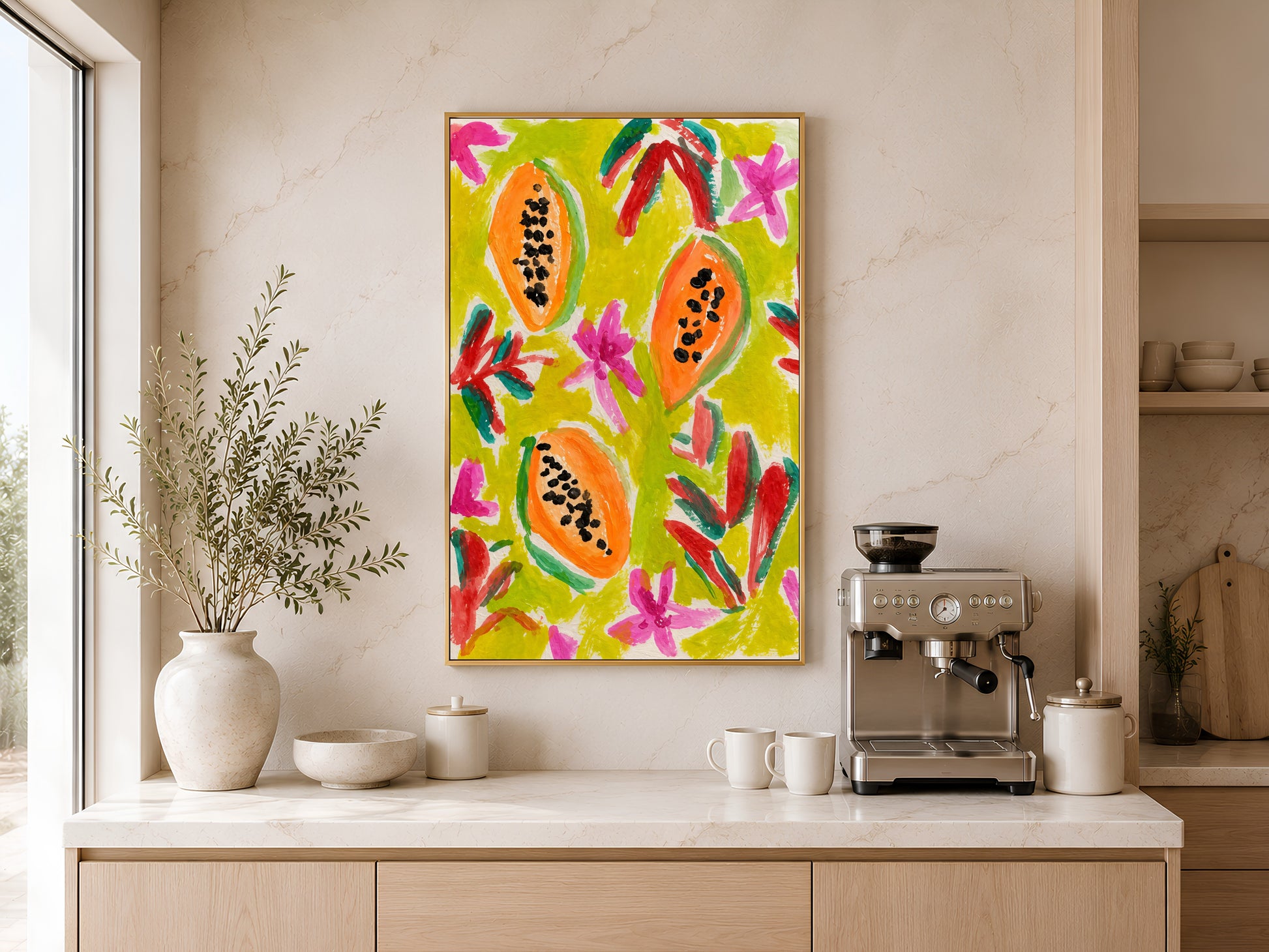 Colorful papaya print in a gold frame displayed above a light wood sideboard in a modern kitchen with neutral tones, pendant lights, and warm natural light
