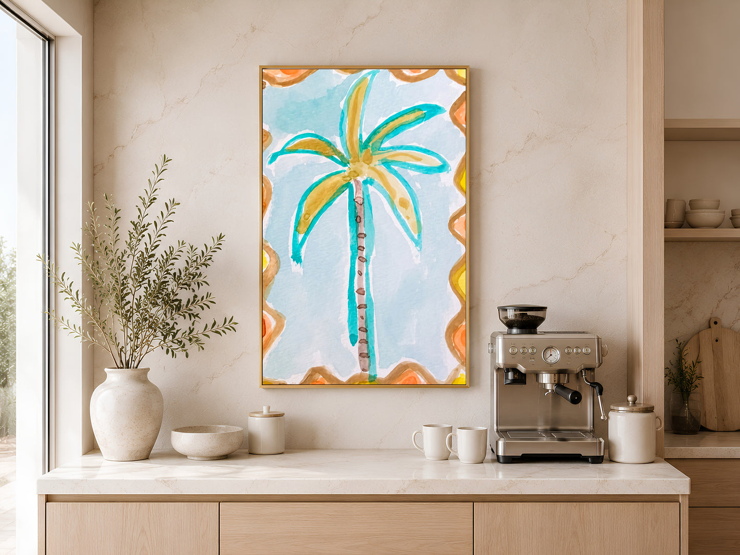 Retro palm tree print in a gold frame displayed above a light wood sideboard in a modern kitchen with neutral tones, pendant lights, and warm natural light
