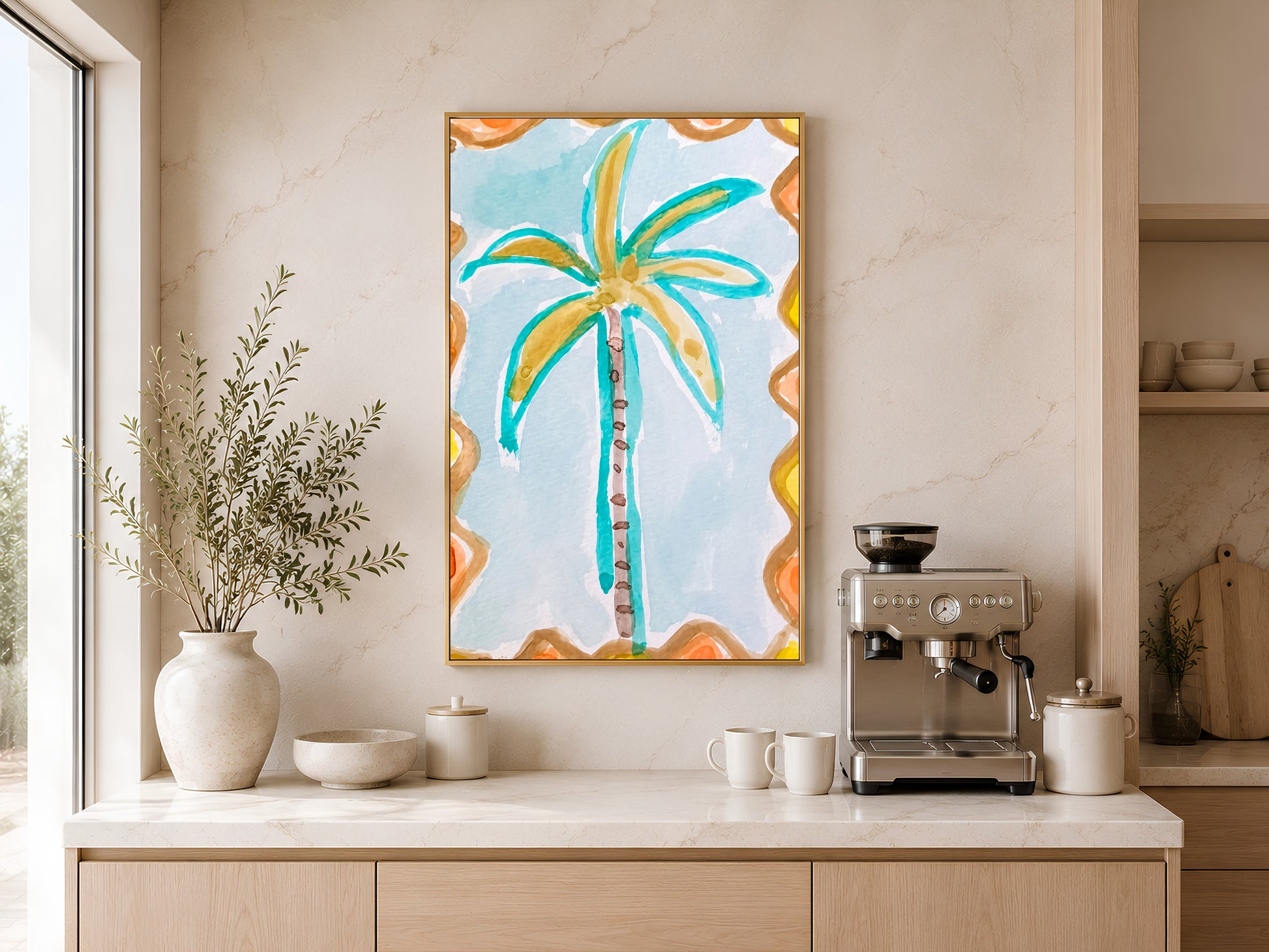 Retro palm tree print in a gold frame displayed above a light wood sideboard in a modern kitchen with neutral tones, pendant lights, and warm natural light
