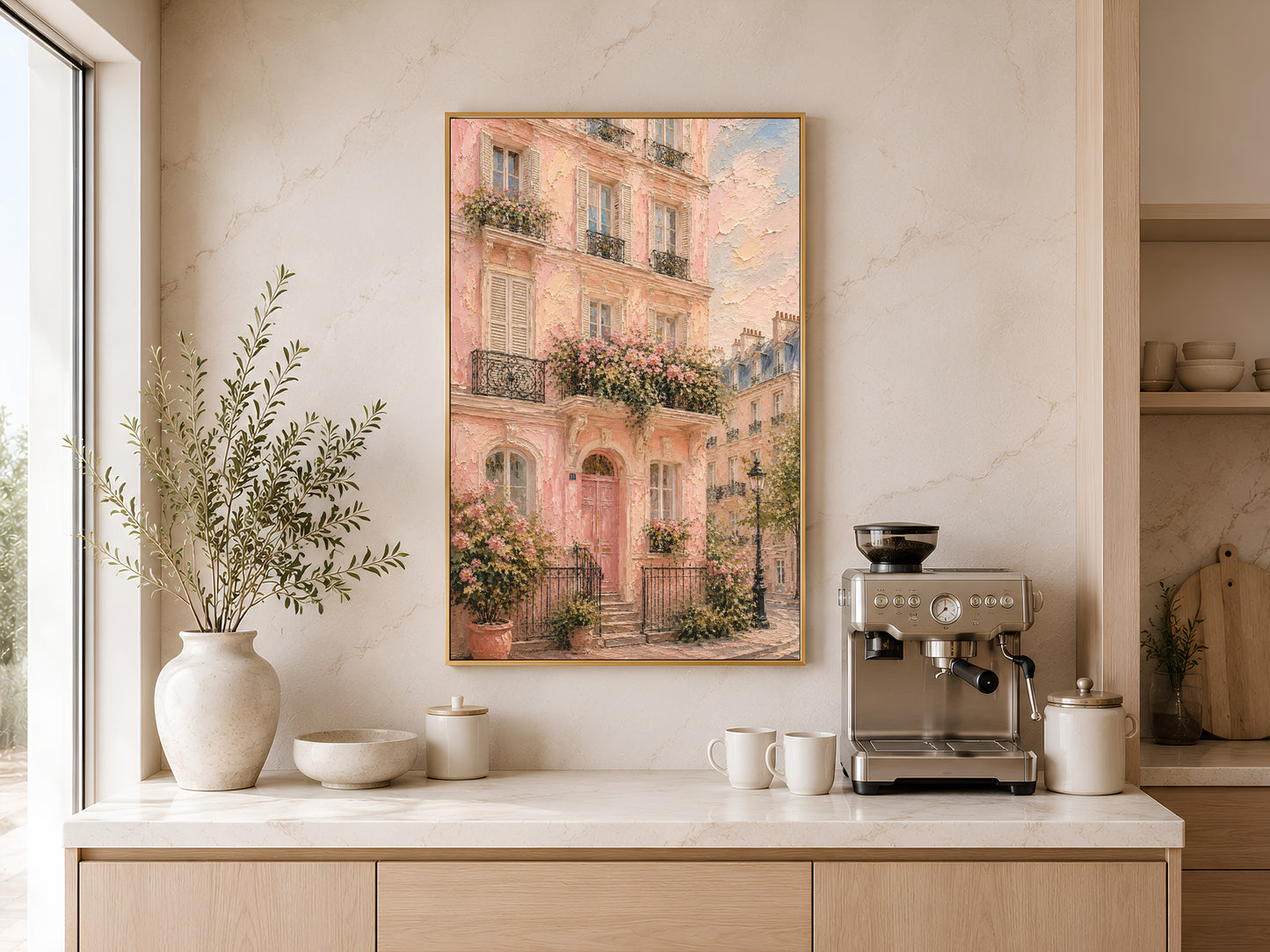 Framed pink Paris building impasto print above a kitchen sideboard with ceramic vases and warm natural light beside a coffee machine
