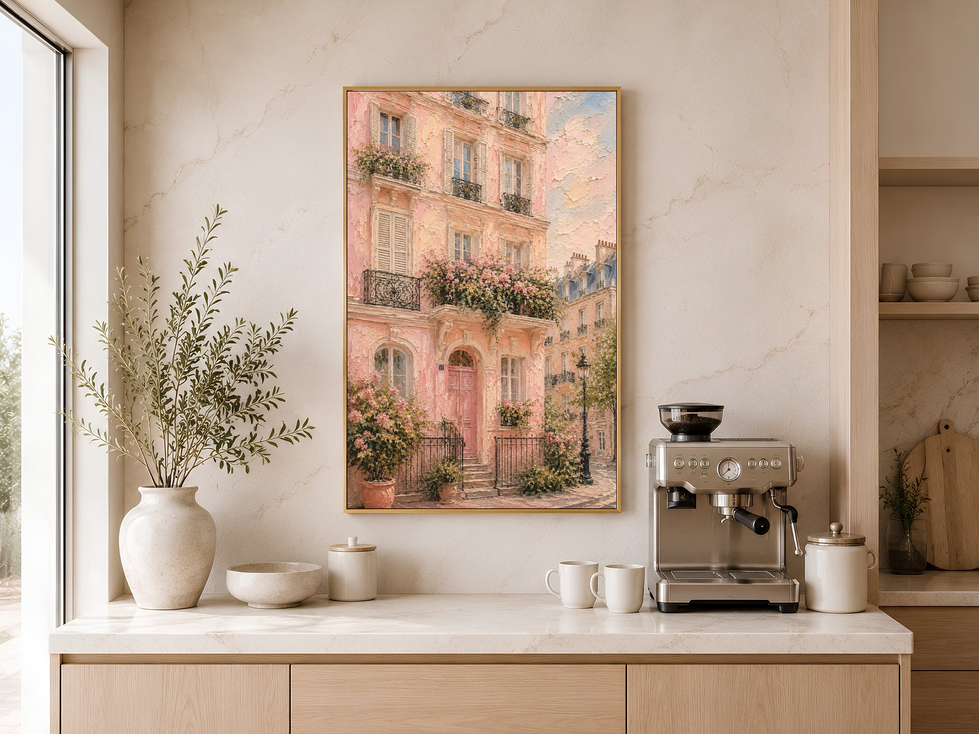 Framed pink Paris building impasto print above a kitchen sideboard with ceramic vases and warm natural light beside a coffee machine
