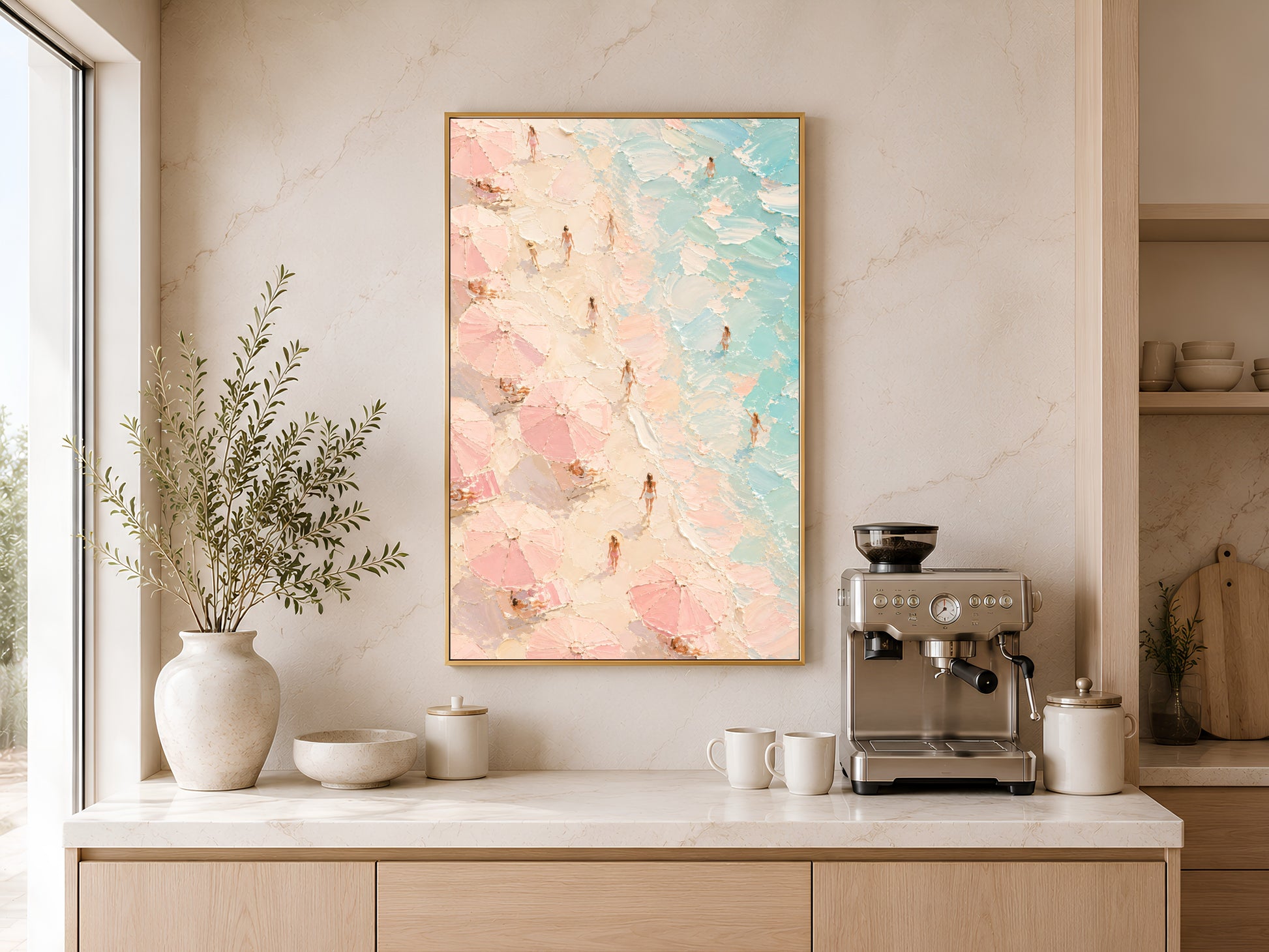 Framed aerial beach painting print in pink and teal on a warm white wall above a kitchen sideboard with neutral vases and wooden dining table
