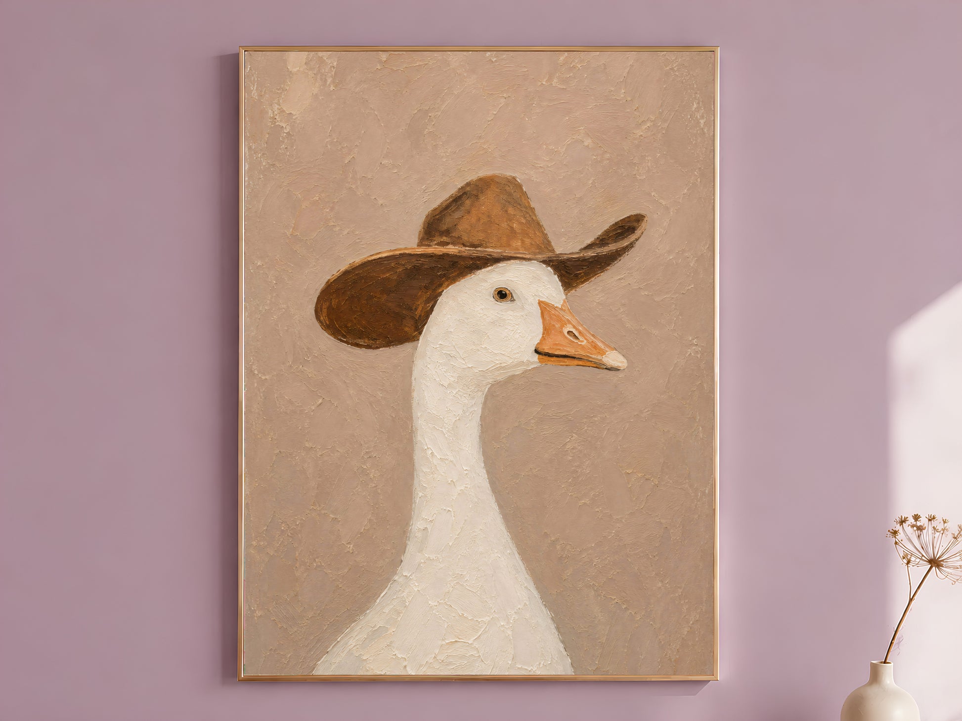 Cowboy goose wall art in a gold frame on a dusty mauve wall with a dried allium stem, showing a white goose in a worn brown cowboy hat painted in thick impasto oil painting style on a warm chalky beige background



