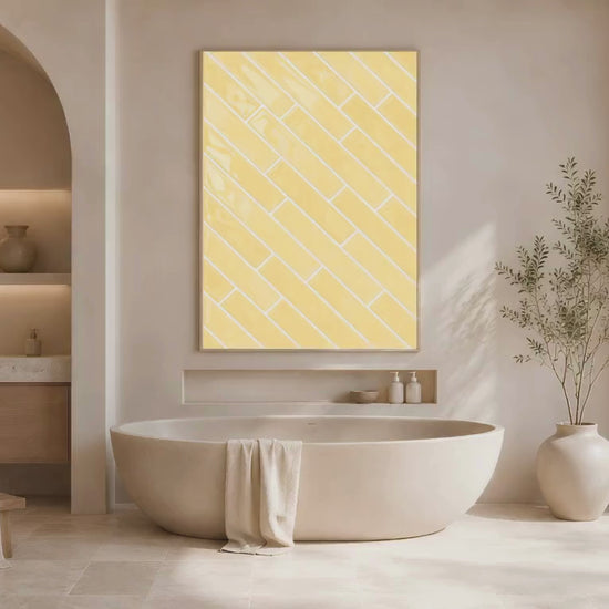 Butter yellow herringbone tile print in a natural wood frame displayed in a warm cream spa bathroom with a freestanding soaking tub and arched mirror