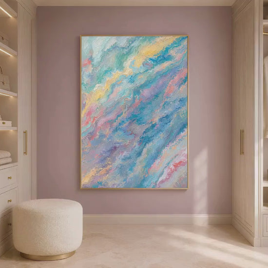 Pastel teal pink abstract swirl print in gold frame leaning against mauve wall on light wood floor with cream ottoman (video)
