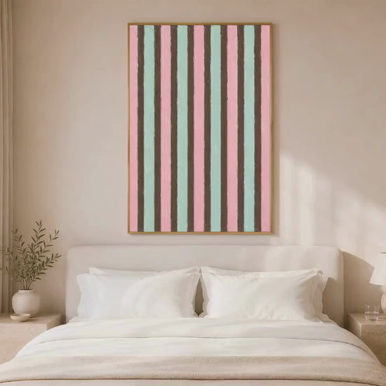 Pink mint candy stripe wall art in gold frame above white bed in warm neutral bedroom with soft lighting 